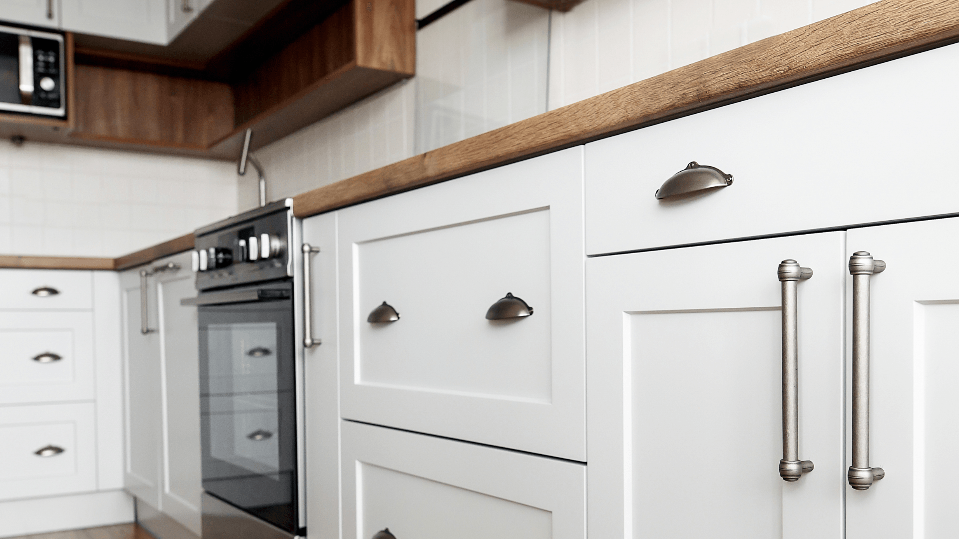Close up of white kitchen cabinet doors and drawers with wooden countertop.
