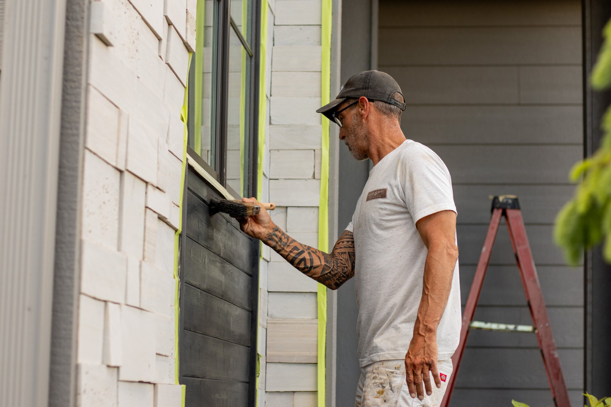 Brush & Roll Painting painter brushing black paint onto wood siding accent on a house in Omaha, NE