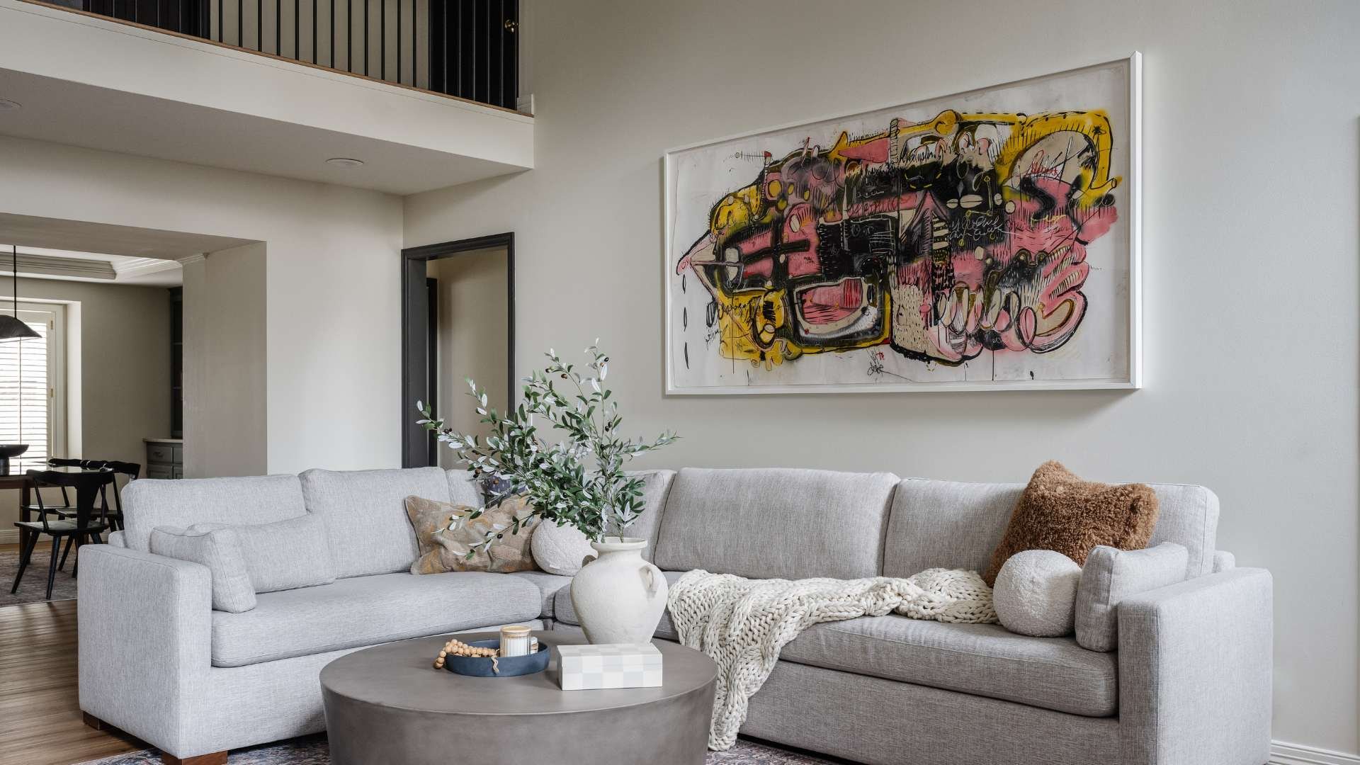 Living room with a large painting hung on white walls and grey couch.